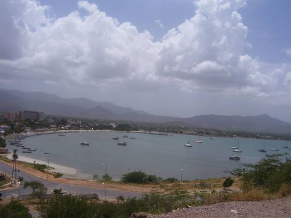Bay with anchored boats, town and mountains under towering clouds, Margarita
