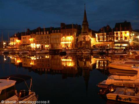 Boats moored at Honfleur harbor at night, lights reflecting on the water