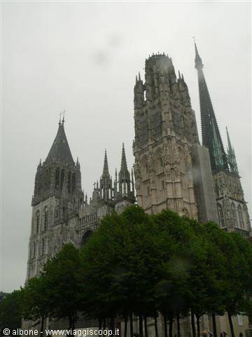 Rouen Cathedral, gothic stone spires under grey sky, trees in foreground
