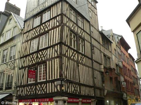 Narrow street corner with tall dark timber-framed house under grey sky