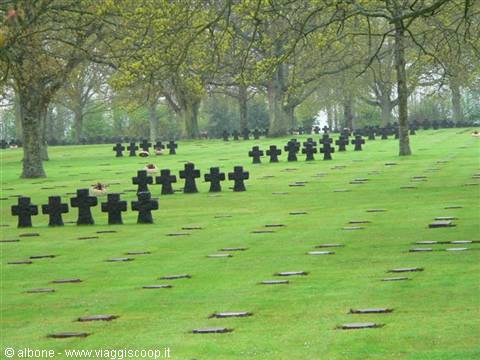 German military cemetery: black stone crosses aligned on green lawn under trees