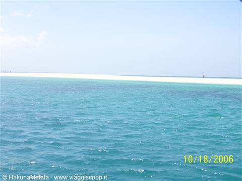 Turquoise water in front of a white sandbar under blue sky