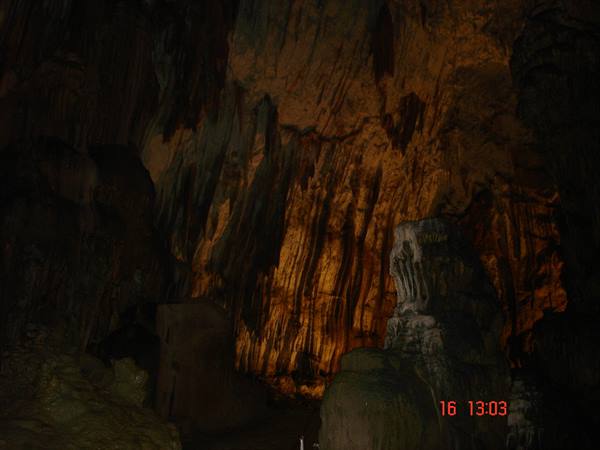 Stalactites and stalagmites in cave lit by orange light
