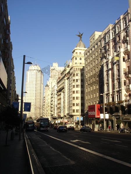 Gran Via in Madrid, traffic flowing under sunlit historic buildings