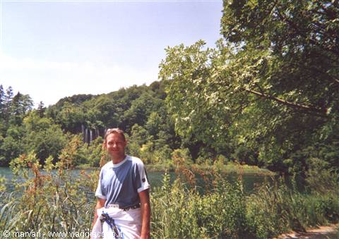Smiling man beside a lake with waterfall, Plitvice Lakes
