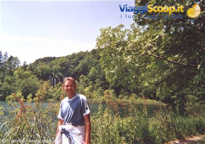 Smiling man beside a lake with waterfall, Plitvice Lakes