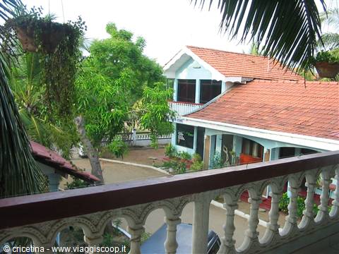 Blue villa with red tile roofs seen from a white balustrade balcony