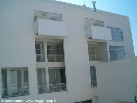 White modern hotel facade with empty balconies under bright sun