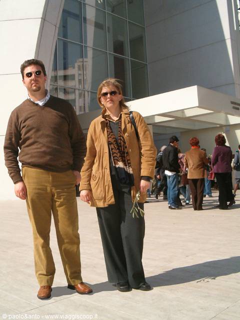 Couple wearing sunglasses in front of modern glass and concrete building