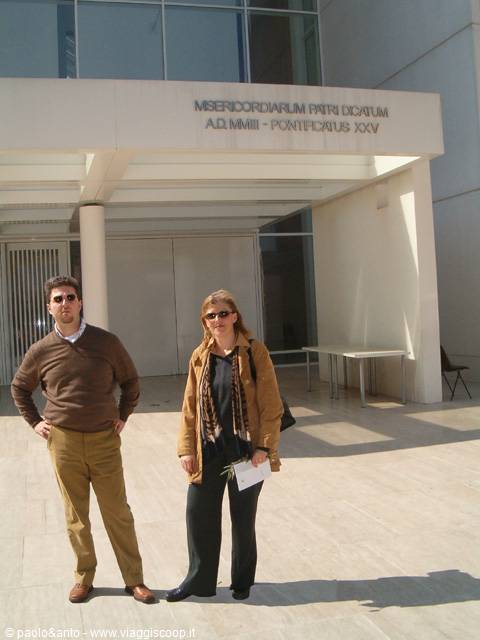 Couple in sunglasses beneath the modern Misericordiarum Pius Dicatum entrance