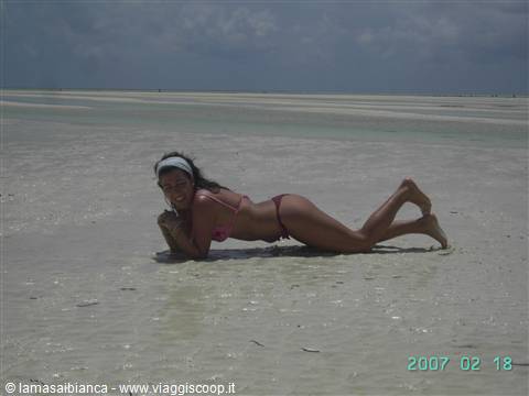 Woman in bikini lying on wet sand at low-tide beach