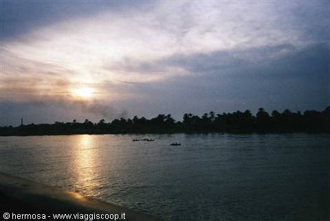 Boats on the river at low light, palm trees silhouetted along the bank