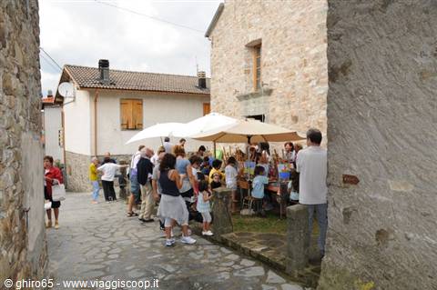 White umbrella market stalls in a stone alley of an Apennine village