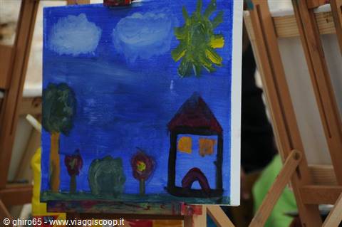 Child's painting of house, sun and flowers propped on wooden easels