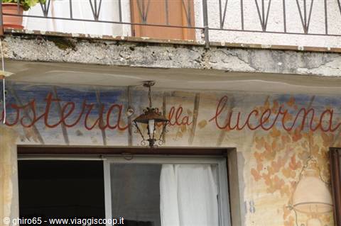 Hand-painted sign of Osteria della Lucerna, with a lantern hanging under the balcony