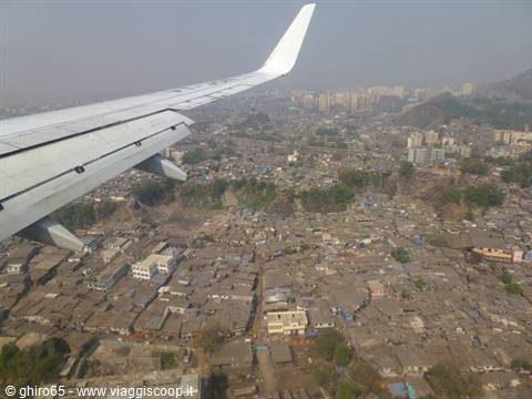 Airplane wing over dense low-rise city, hazy light