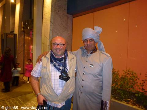 Tourist posing with a turbaned doorman in grey uniform outside a hotel