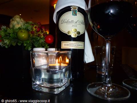 Dolcetto d'Alba wine bottle with glass and floating candle on table