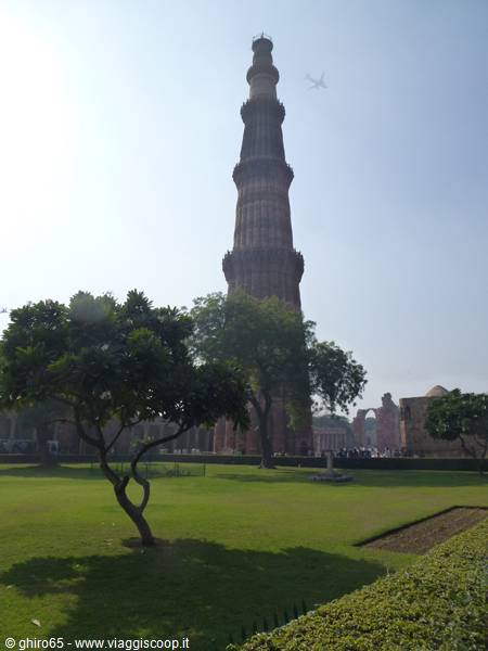 Qutb Minar in Delhi rises in red sandstone among trees and green gardens