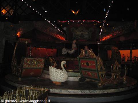 Indoor carousel with white swan and golden gondolas under string lights