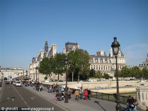 Tourists walk along the Seine in front of Paris' Hôtel de Ville