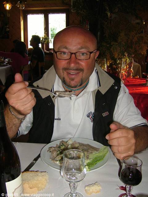 Man with glasses holding fork, eating mushrooms at trattoria table