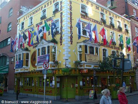 Yellow pub facade covered with international flags and traditional music signs