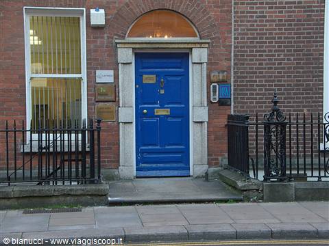 Blue door on red brick facade behind wrought iron railings