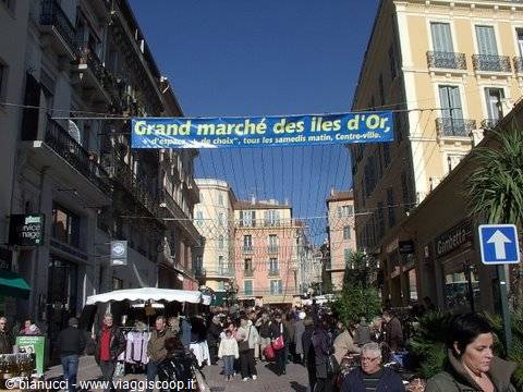 Crowded street with blue Grand Marché des Iles d'Or banner between colorful buildings