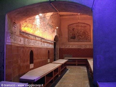 Inside a hammam: tiled masonry benches, golden mosaic and warm lighting