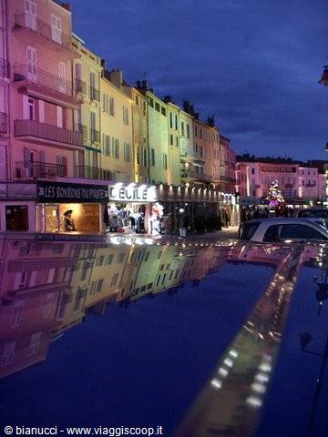 Boats in the harbor in front of illuminated colorful houses in Saint-Tropez