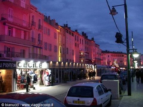 Evening lane with pastel buildings, illuminated shops and parked cars
