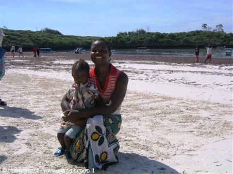 Smiling woman holding a child on white sand beach