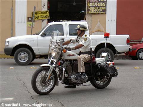 Uniformed policeman rides a police motorcycle next to a white pickup truck