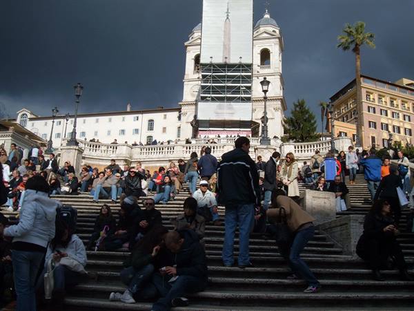 Tourists sitting on the Spanish Steps under a cloudy sky