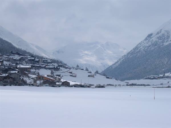 Snow-covered alpine village with white rooftops beneath overcast mountains