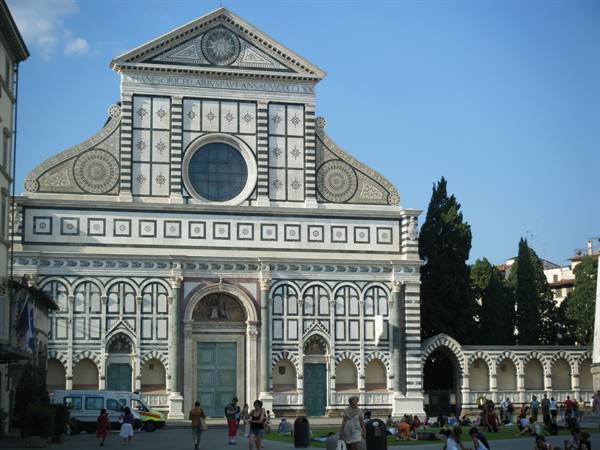 White and green marble facade of Santa Maria Novella, tourists relaxing on the square