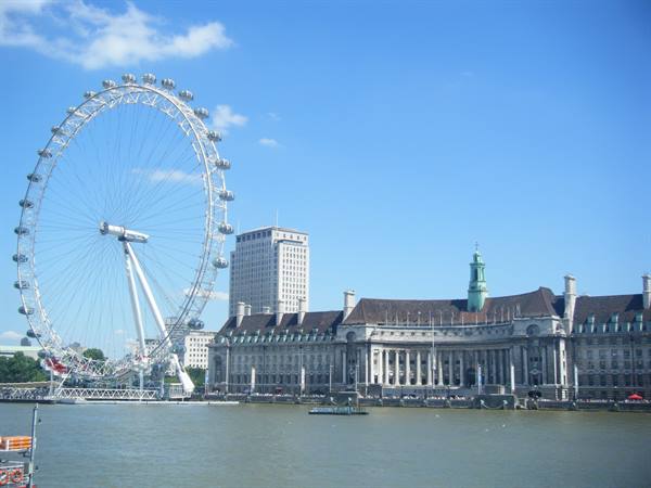 The London Eye and County Hall by the Thames under blue sky