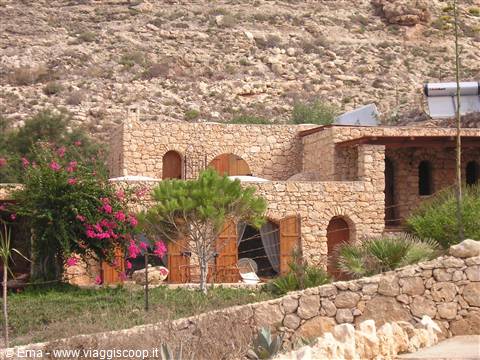 Stone house with arches and flowering bougainvillea among dry hills