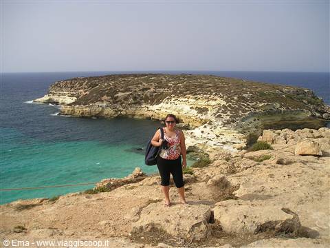 Tourist posing on limestone rocks in front of Rabbit Island, Lampedusa
