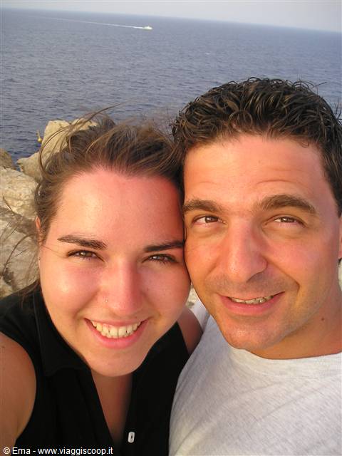 Smiling couple taking a selfie above rocky cliffs and open sea