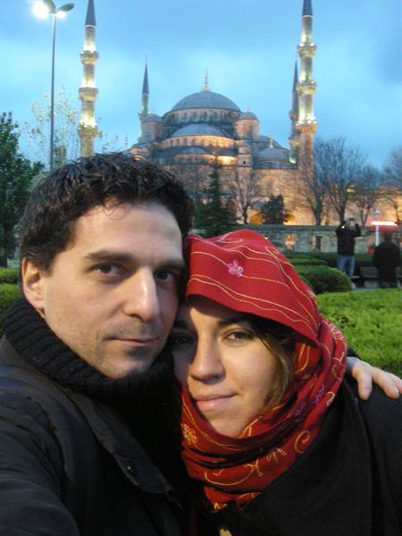 Couple posing in front of Istanbul's Blue Mosque illuminated at dusk