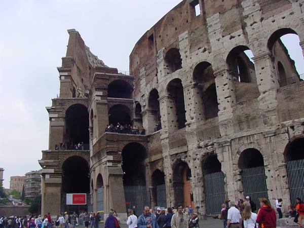 Tourists beneath the brick arches of the Colosseum in Rome, grey sky