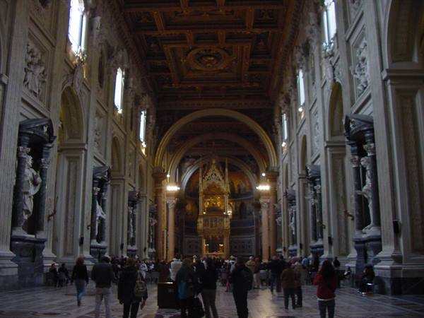 Visitors inside the Basilica of St. John Lateran among statues and gilded ceiling