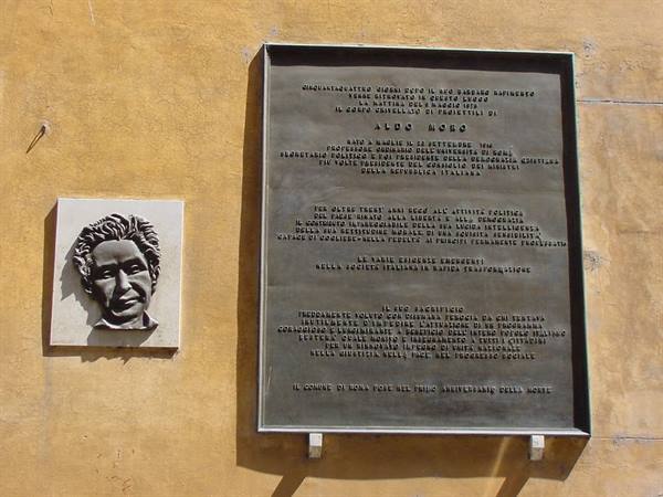 Bronze plaque with relief and marble portrait on the yellow wall