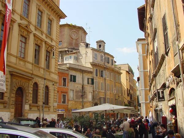 Crowd under white umbrellas at Campo de' Fiori market among ochre historic buildings