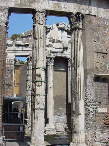 Weathered Corinthian columns of Portico di Ottavia among ancient brick walls