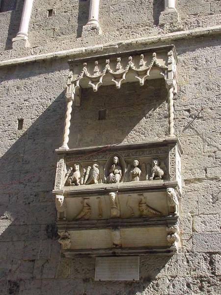 Medieval stone pulpit with carved canopy and statues on ancient walls