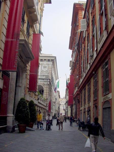 Garibaldi street in Genoa, colorful buildings with red banners and pedestrians