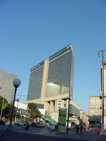Skyscraper at Naples Centro Direzionale, traffic and pedestrians under blue sky